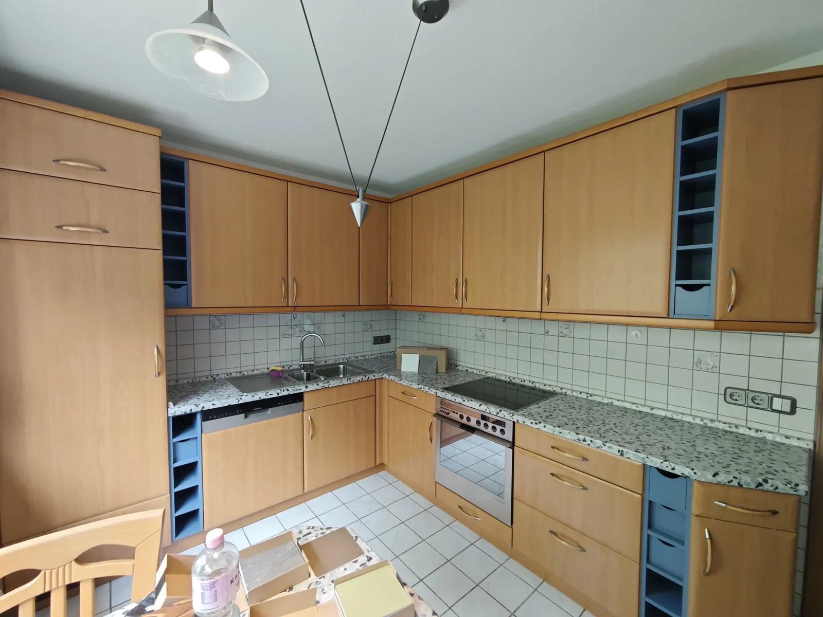 L-Küche vorher: Fronten in Buche-Optik, weißer Fliesenspiegel und Terrazzo-Arbeitsplatte