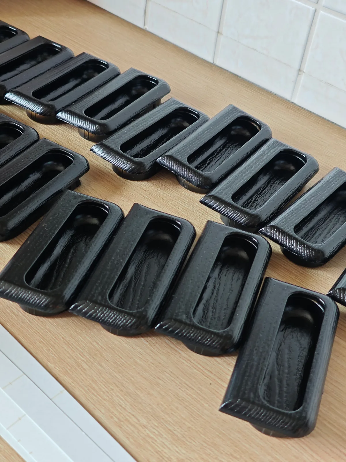 Reihe fachmännisch schwarz lackierter Einbaugriffe aus Holz nach der Aufbereitung